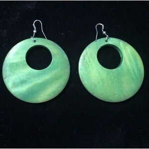 Circular wooden earrings painted in a vibrant green, with a watercolor finish.
